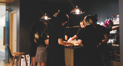 A group of multicolored diverse people discussing renovation progress around a kitchen island.