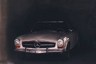 A sleek vintage car parked in a dimly lit luxury garage with golden accents.