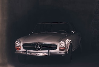 A restored classic luxury car gleaming under soft studio lighting with a dark background emphasizing its elegant curves.