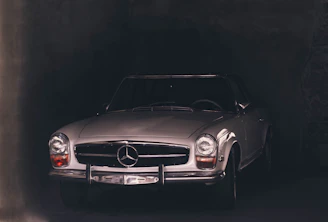 A sleek vintage car parked in front of a dark brick wall, highlighting its elegant curves and timeless design.