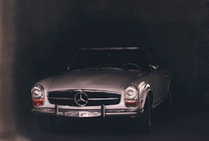 Moody nighttime shot of a classic roadster with gleaming bodywork and illuminated dashboard, set against a dark modern garage backdrop