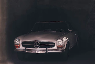 Moody nighttime shot of a classic roadster with gleaming bodywork and illuminated dashboard, set against a dark modern garage backdrop