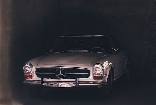 A restored classic luxury car gleaming under soft studio lighting with a dark background emphasizing its elegant curves.