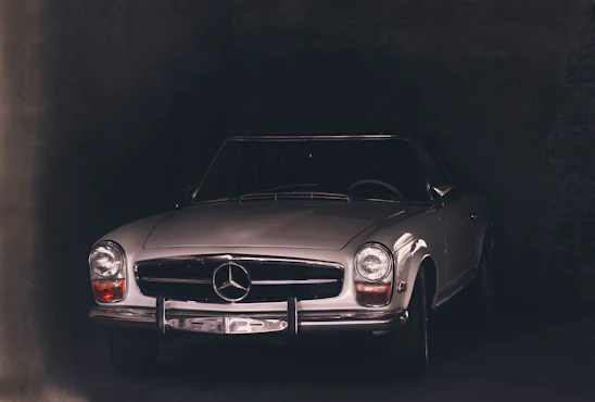 A sleek vintage car parked in front of a dark brick wall, highlighting its elegant curves and timeless design.