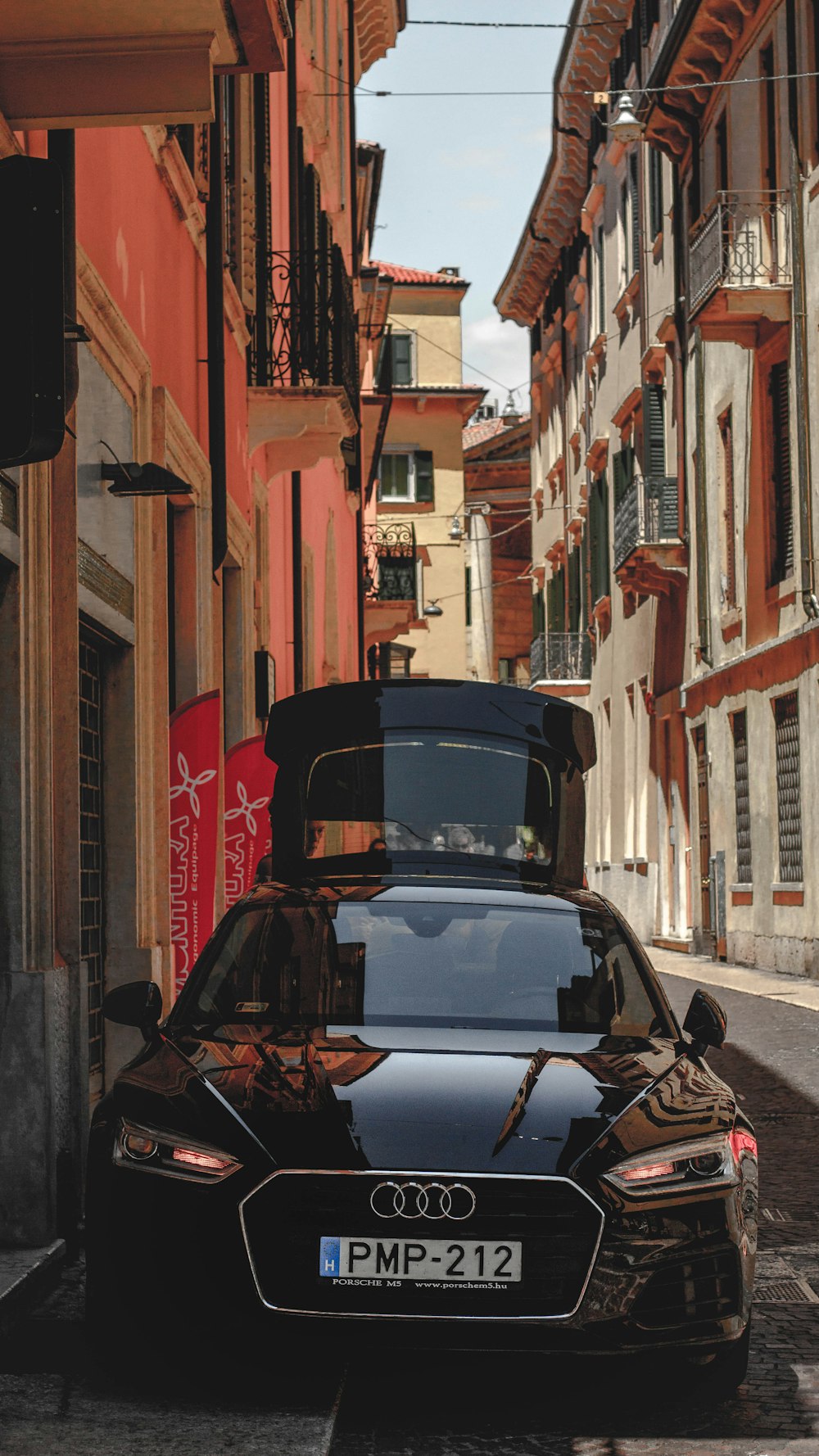 black car parked beside brown building during daytime