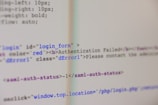 A close-up view of HTML code on a computer screen includes a login form with an error message indicating 'Authentication Failed'. The text has some parts styled in red, signifying an error or warning message.