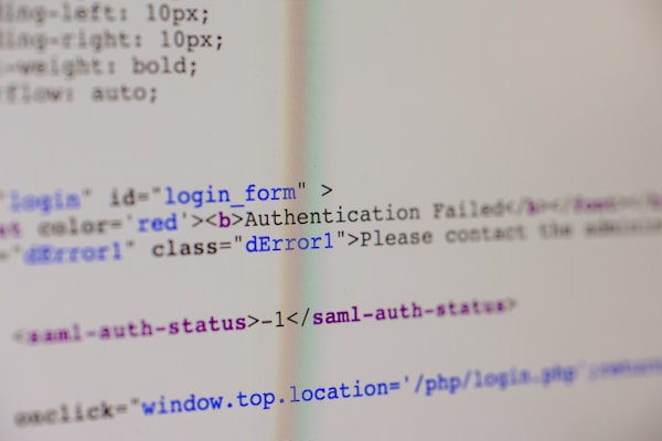 A close-up view of HTML code on a computer screen includes a login form with an error message indicating 'Authentication Failed'. The text has some parts styled in red, signifying an error or warning message.