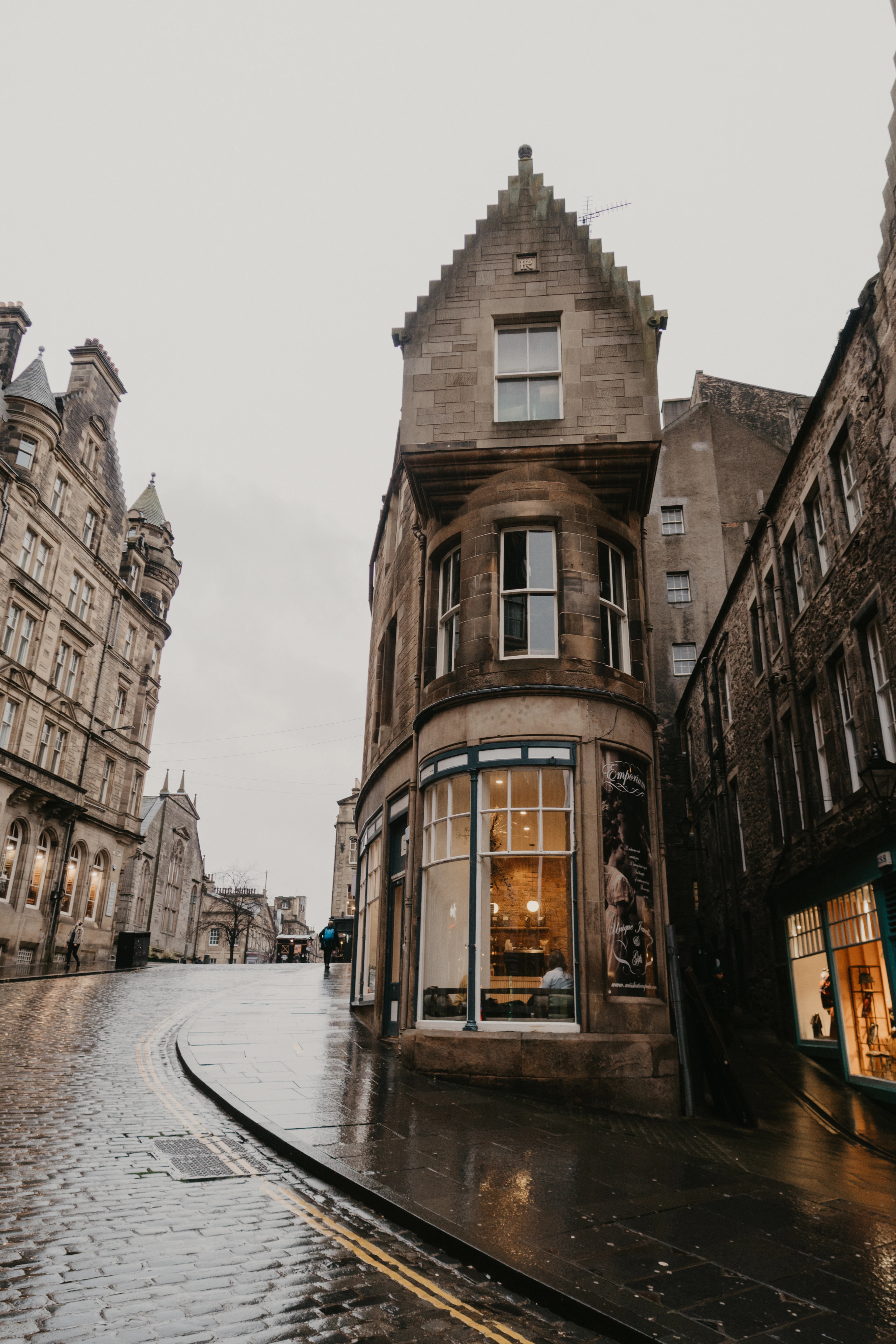A lamplit Old Town corner building glistens on a rainy cobbled street.