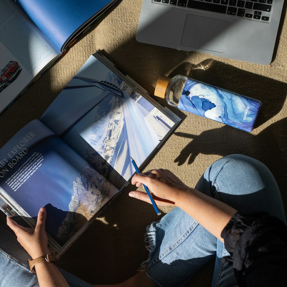 person in blue denim jeans holding blue pen