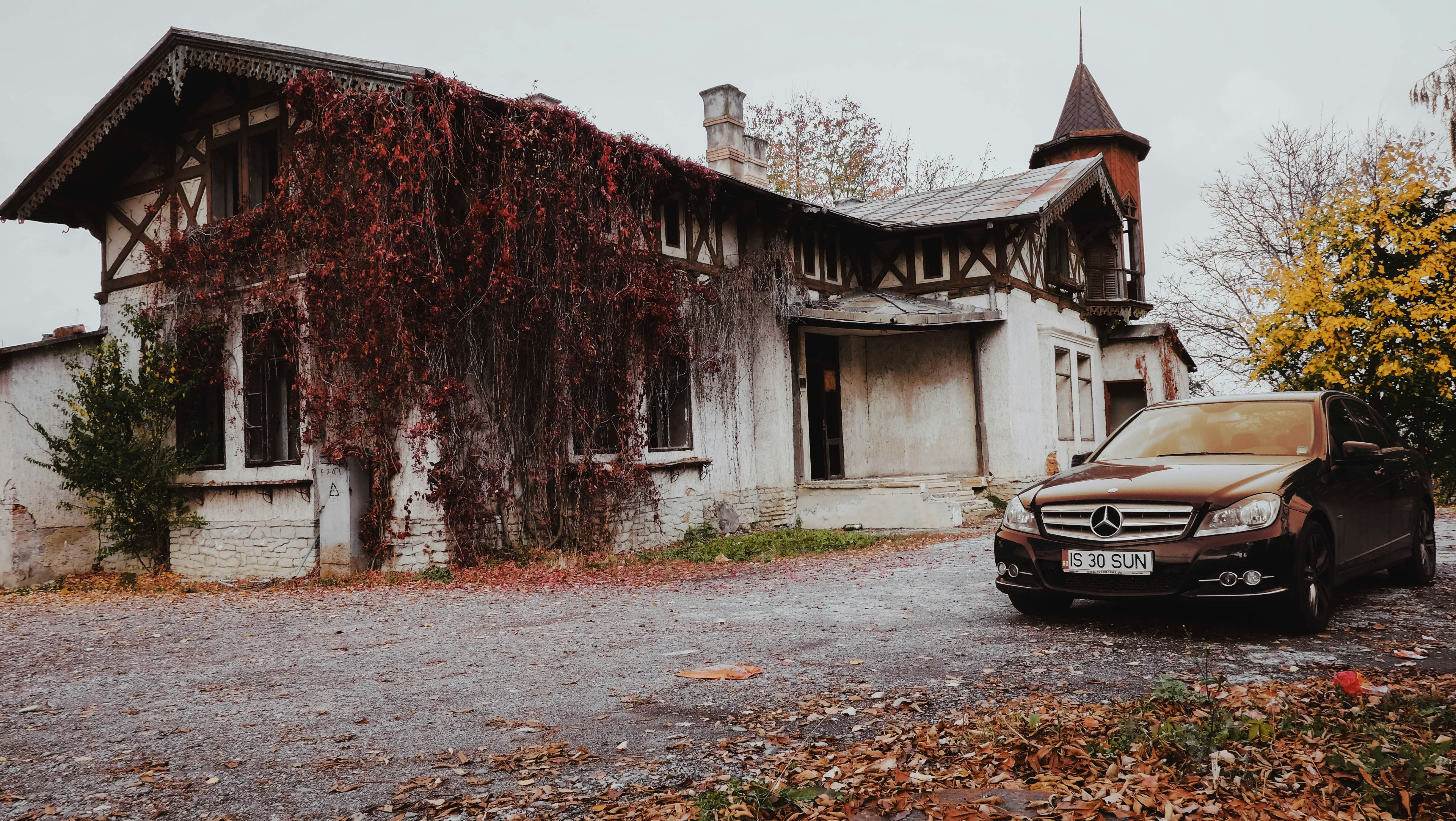 black car parked beside brown wooden building during daytime
