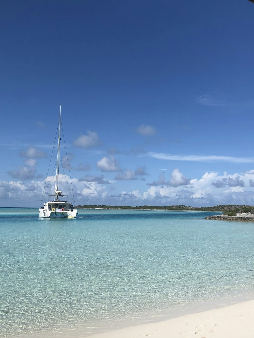 barca bianca sul mare blu sotto il cielo blu durante il giorno