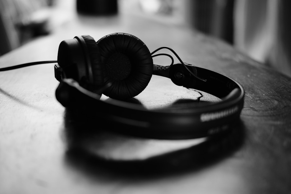 Close-up of sleek black headphones resting on a wooden table with soft natural light highlighting the texture.