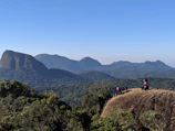 A couple enjoying a scenic mountain view under a clear blue sky with golden sunlight.