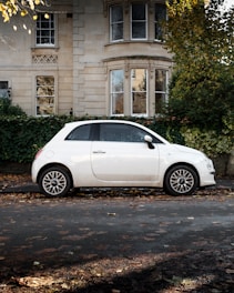 white 5 door hatchback parked beside brown concrete building during daytime