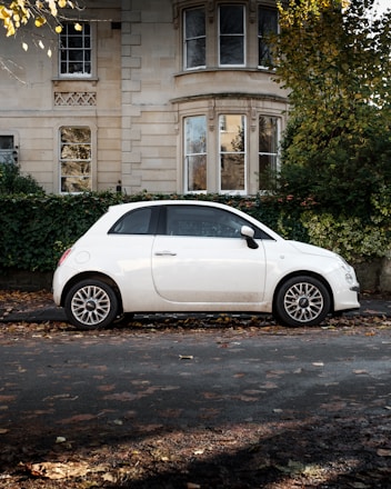 white 5 door hatchback parked beside brown concrete building during daytime