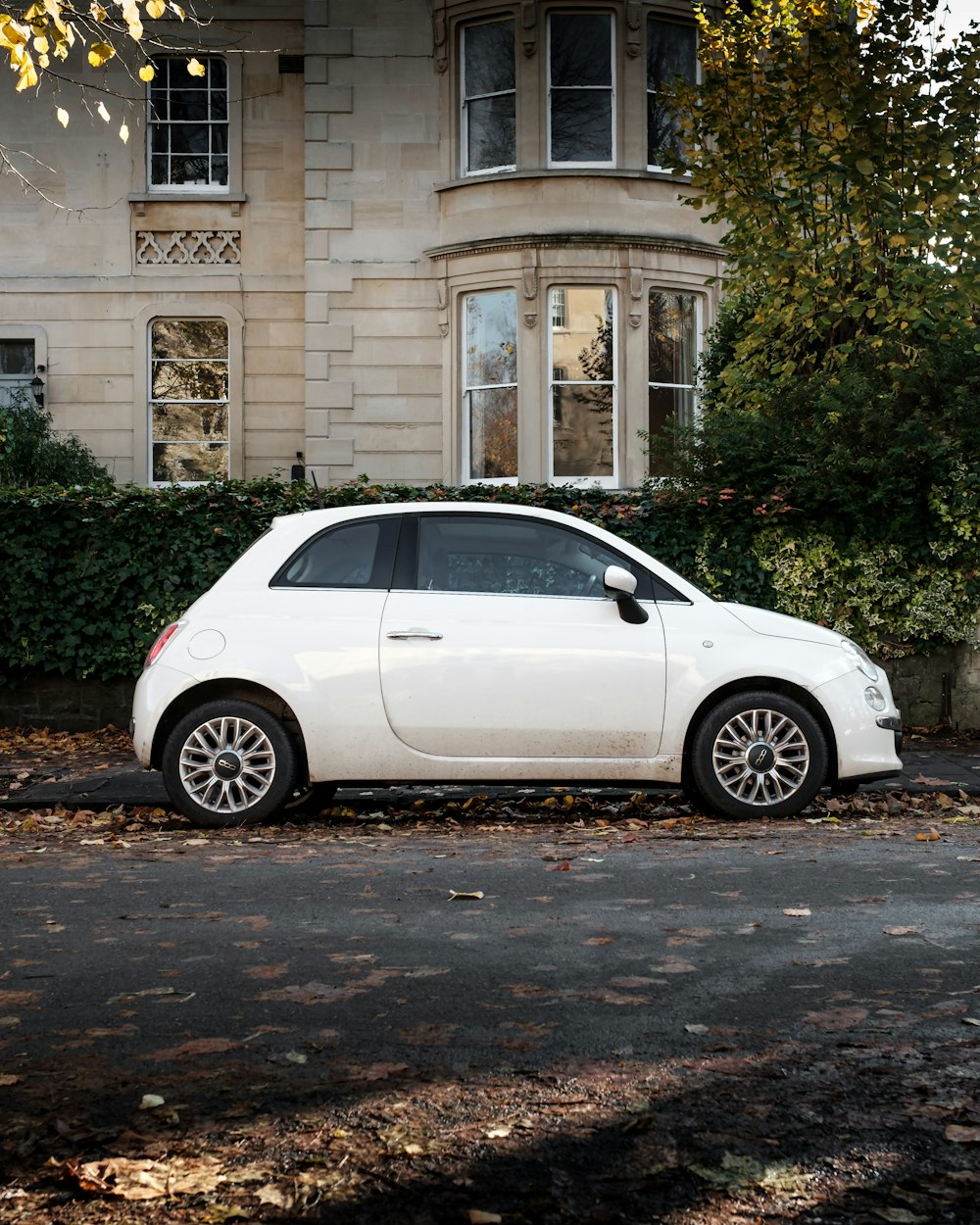 white 5 door hatchback parked beside brown concrete building during daytime