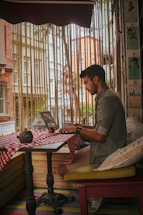 A friendly small business owner using a laptop in a cozy cafe setting.