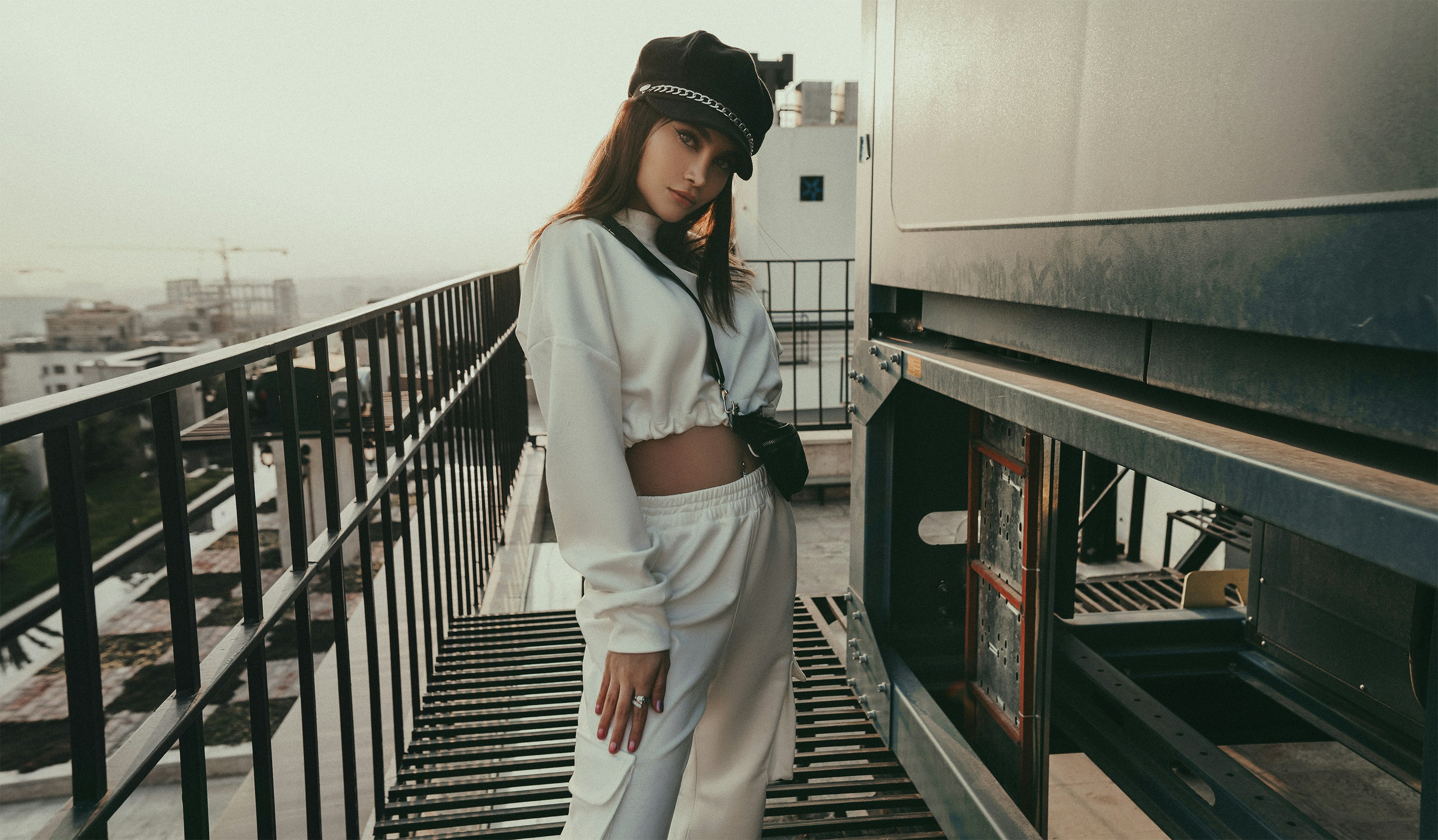 woman in white long sleeve shirt and white pants standing on gray metal railings during daytime