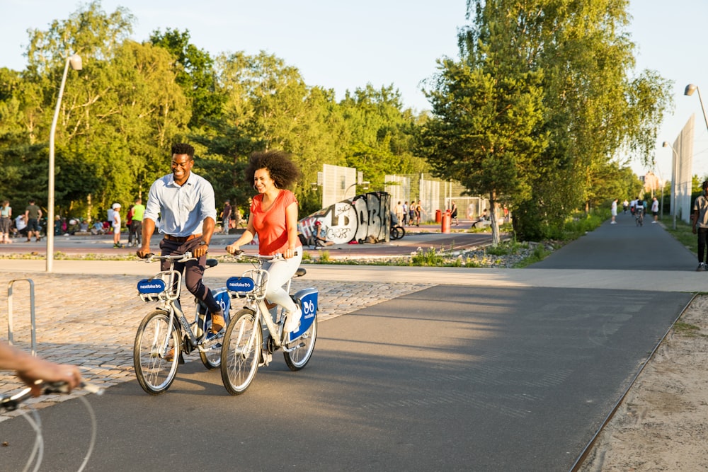 man and woman riding on bicycle on road during daytime