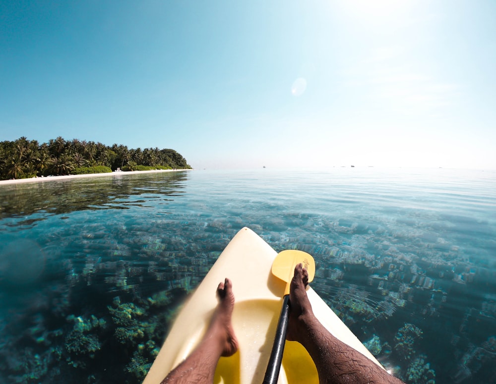 person sitting on white chair near body of water during daytime