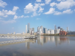 city skyline across body of water under blue and white sunny cloudy sky during daytime