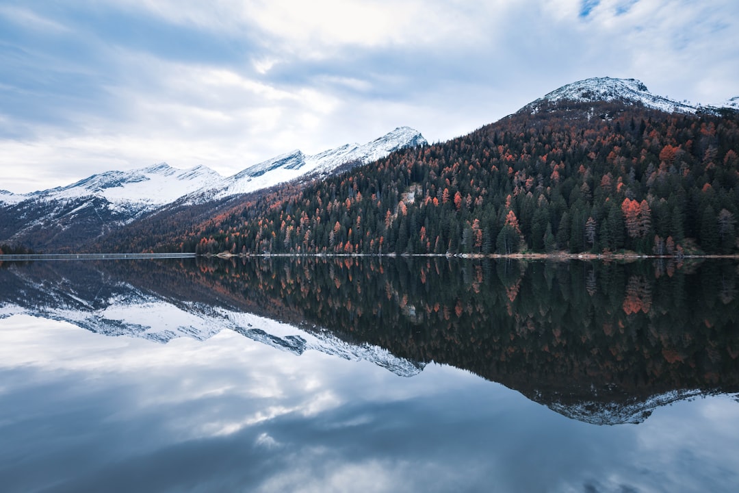 body of water near mountain under cloudy sky during daytime