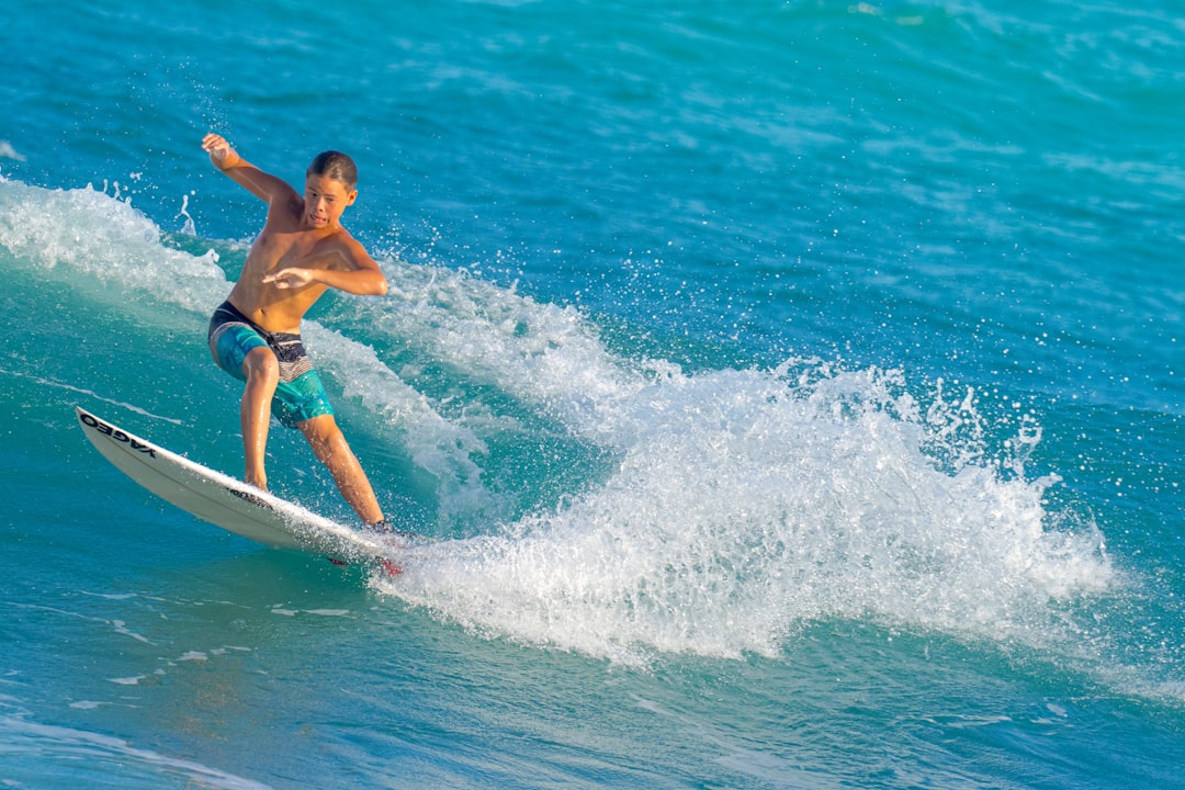 woman in blue bikini surfing on sea waves during daytime