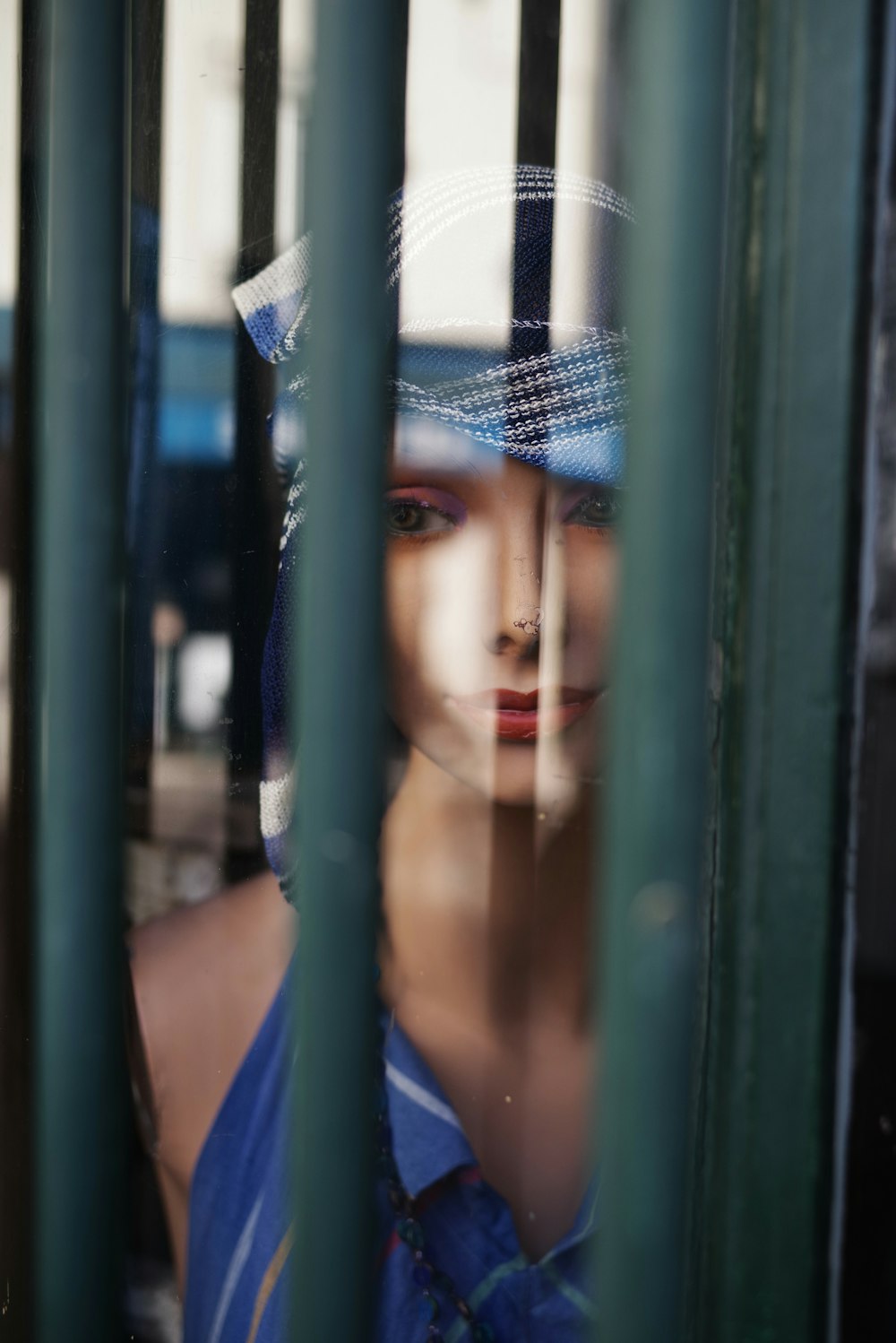 woman in blue and white polka dot hijab leaning on green metal gate