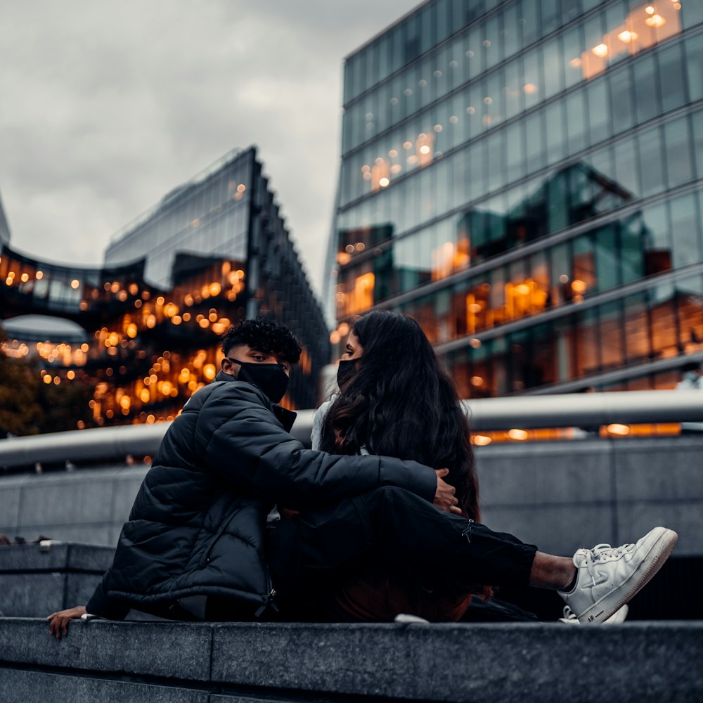 man and woman sitting on gray concrete bench during daytime