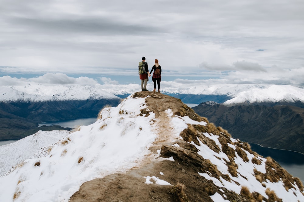 2 men standing on rocky mountain during daytime