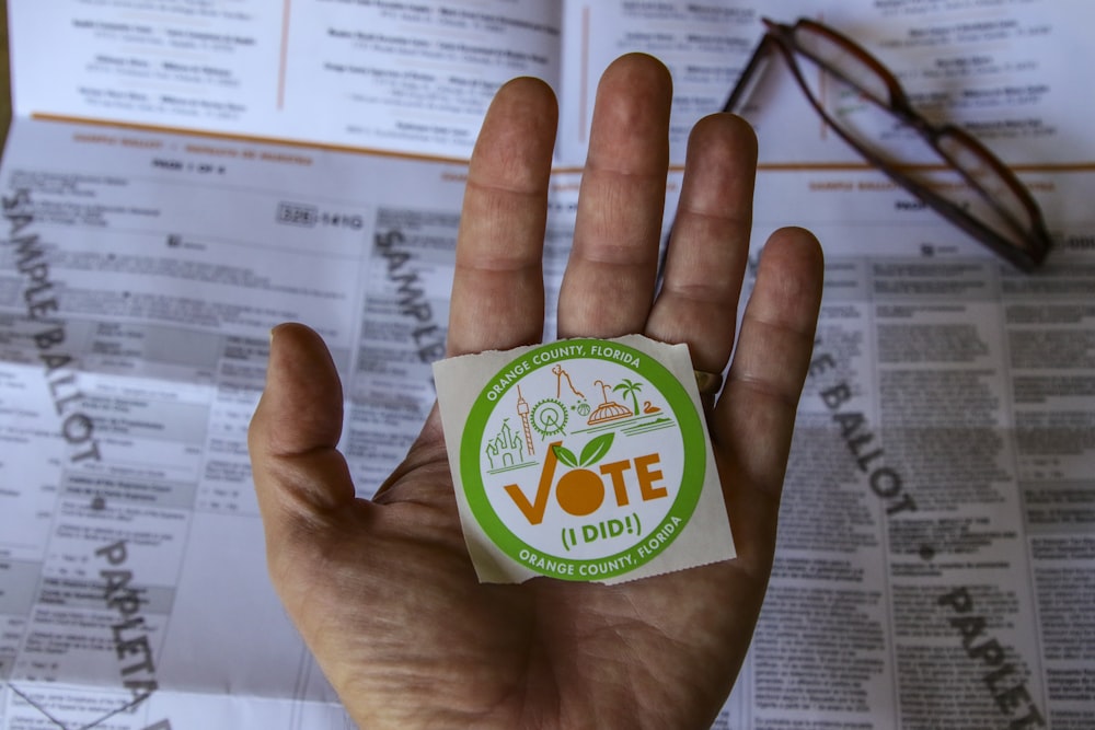 person holding green and white round plastic container