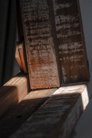 Close-up of skilled hands restoring natural wood beams with fine tools in a luxury lake home.