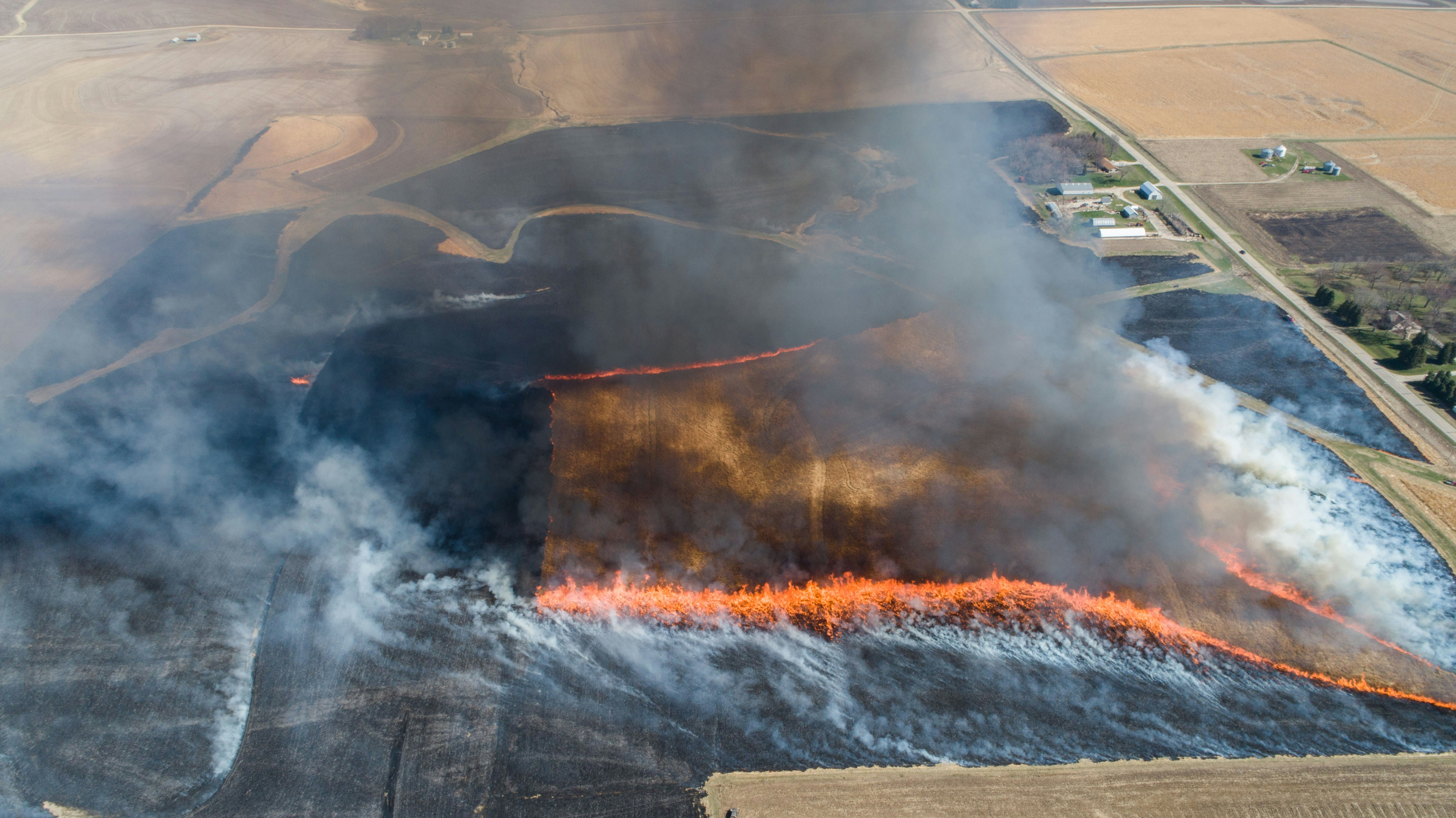 Drone shot of massive controlled prairie burn surrounded by rural farmland.