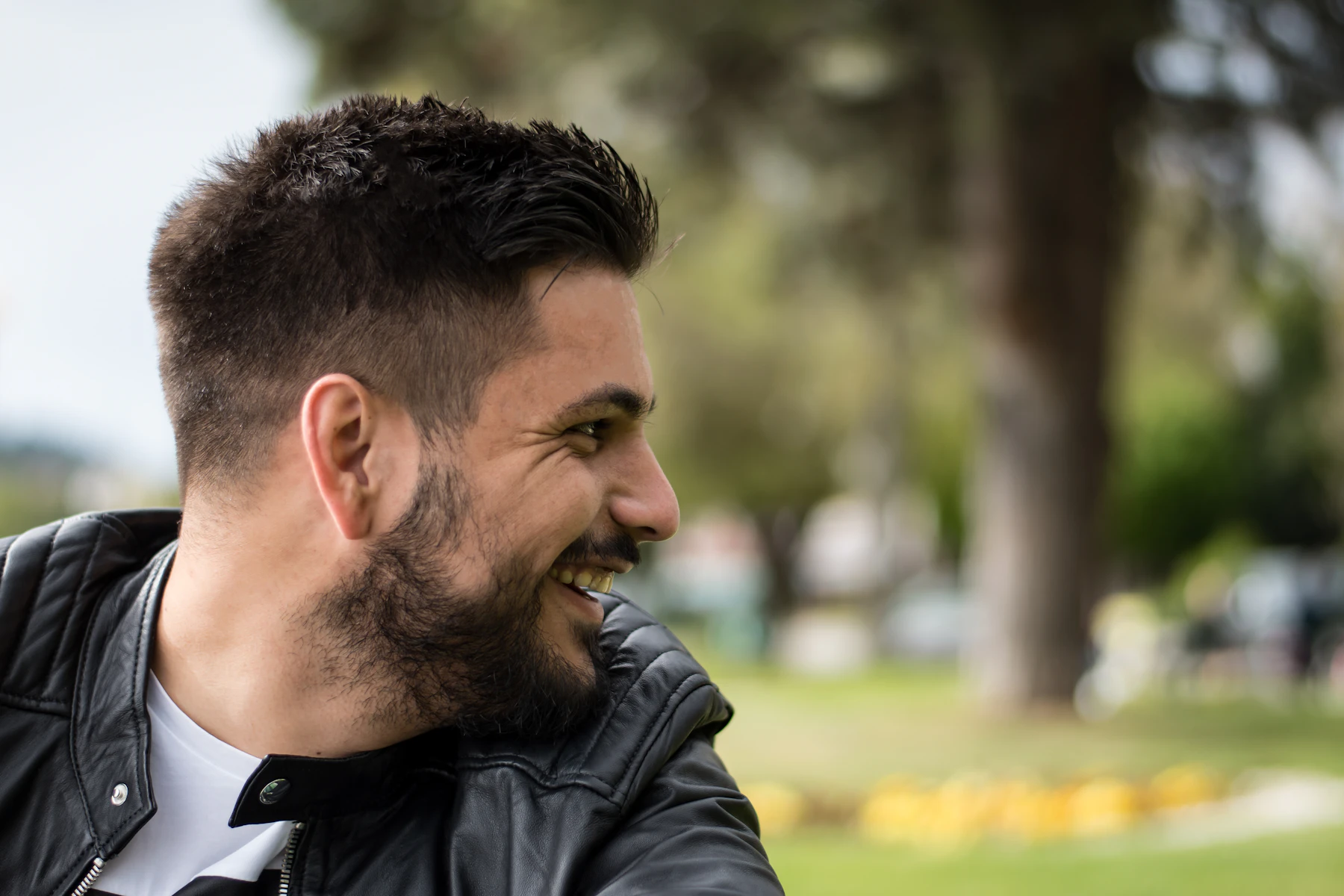 A smiling man with full, styled dark hair