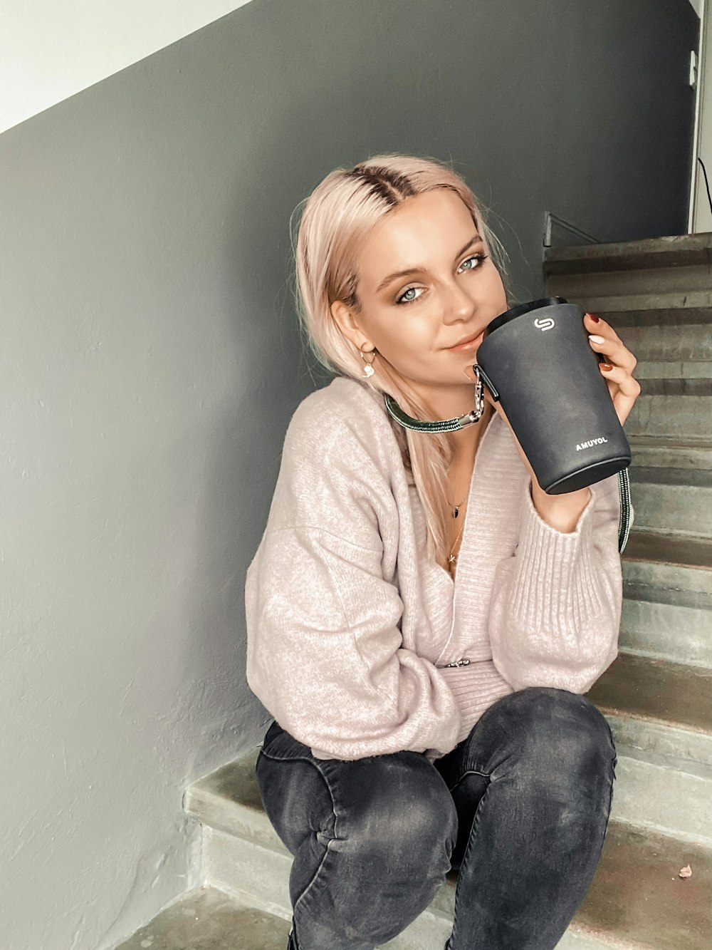 girl in beige sweater holding black ceramic mug