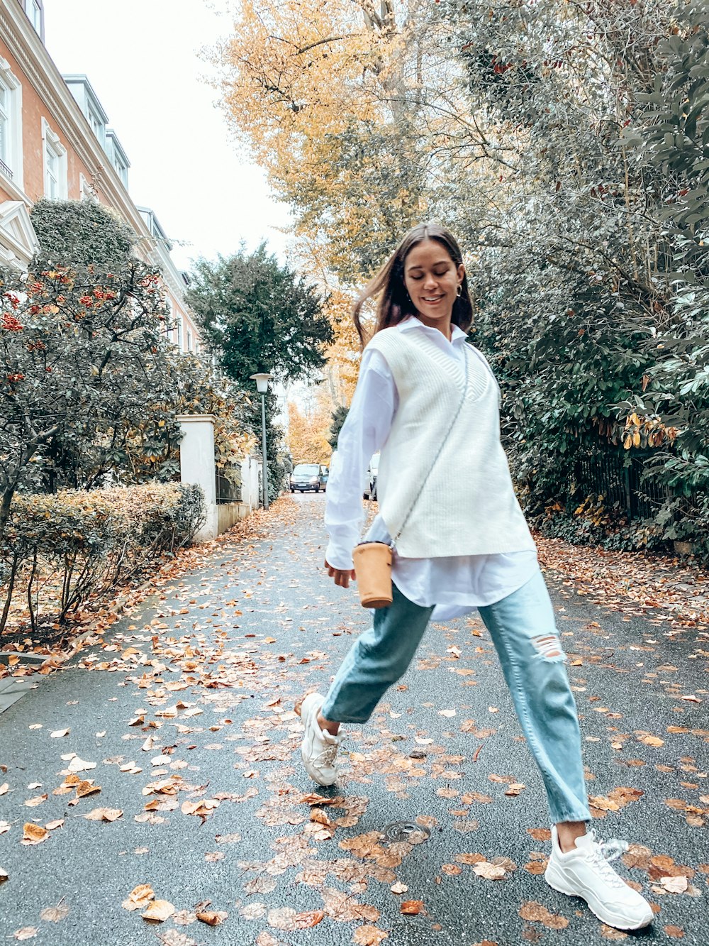 woman in white coat standing on brown leaves during daytime