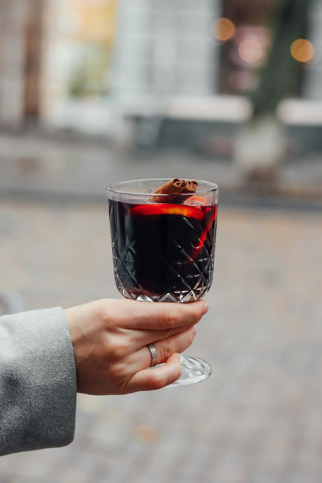 person holding clear drinking glass with red liquid