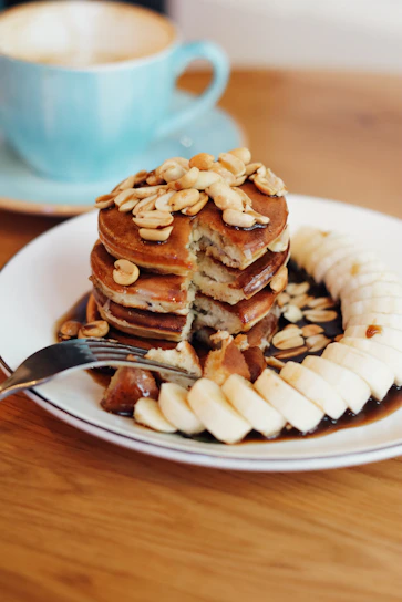 A colorful bowl of protein-packed vegan pancakes topped with fresh banana slices and nuts.