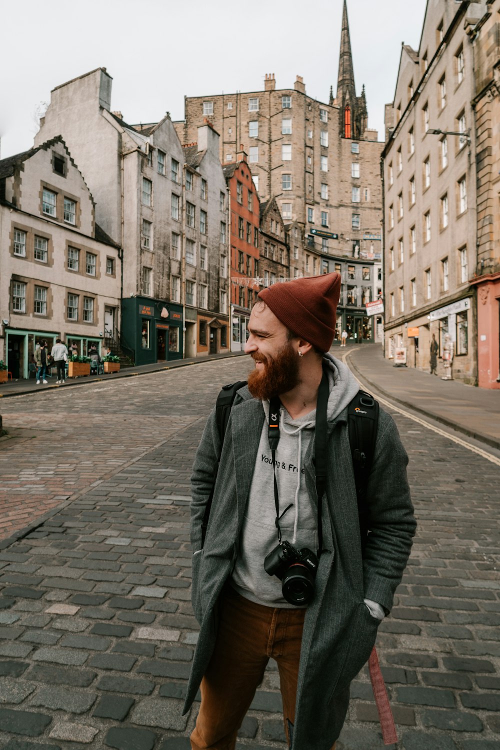 man in black leather jacket wearing brown hat standing on sidewalk during daytime