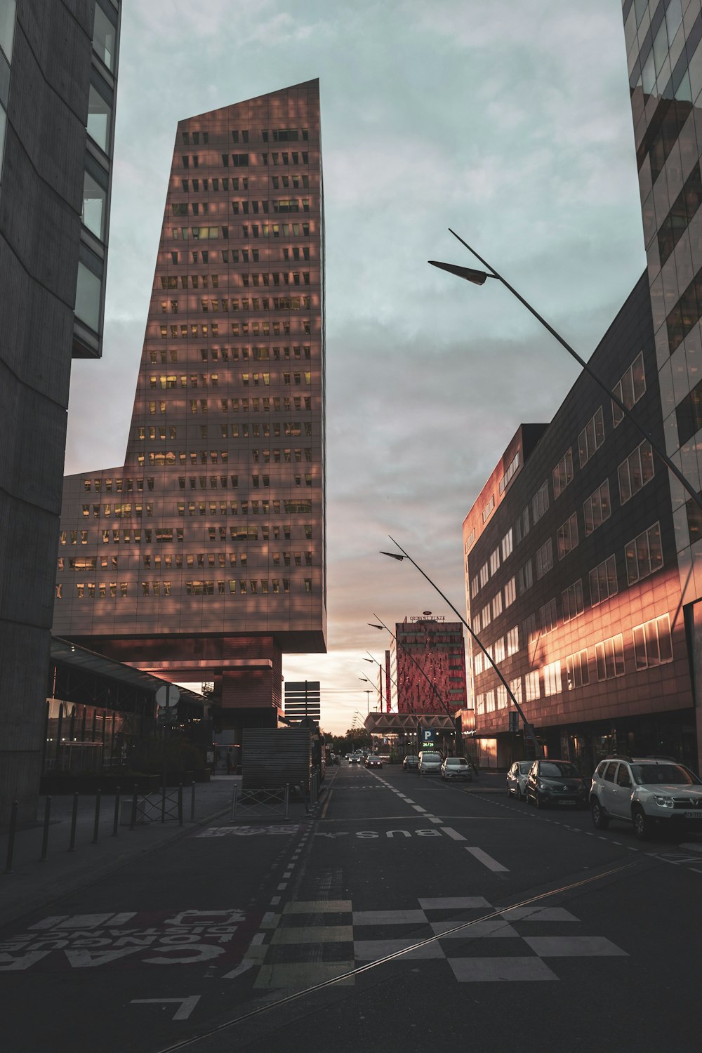 cars parked on side of the road near high rise buildings during daytime