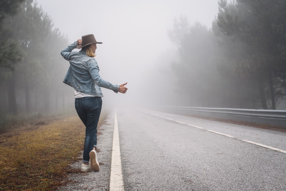 Femme en veste en jean bleu et jean bleu marchant sur la route pendant la journée