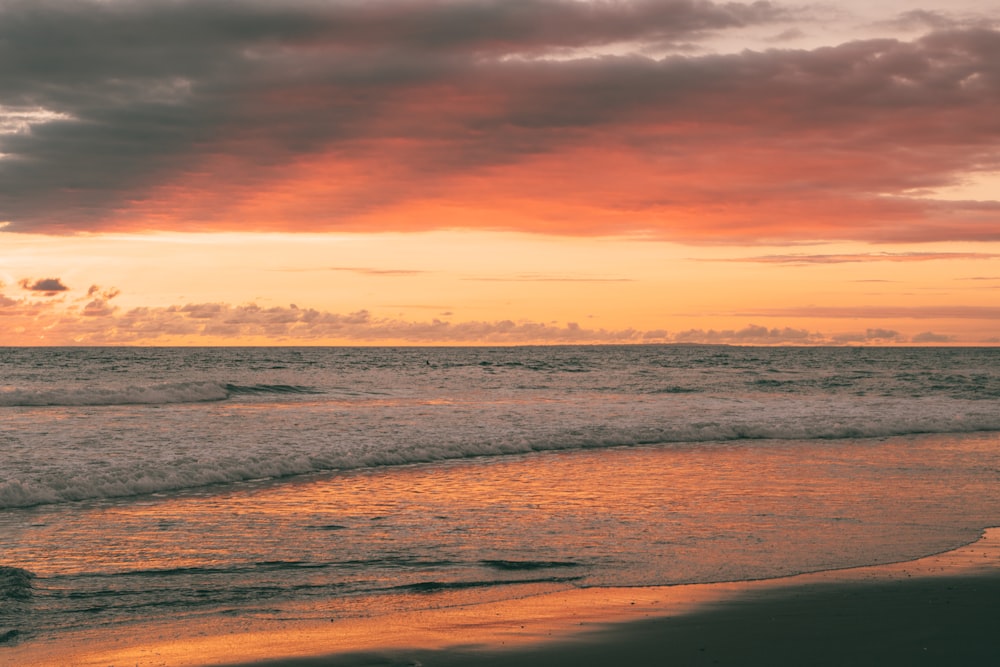 ocean waves crashing on shore during sunset