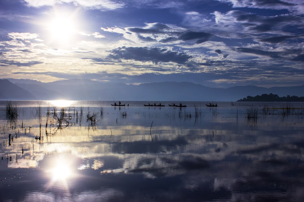 Eine Gruppe von Booten schwimmt auf einem See unter einem bewölkten Himmel