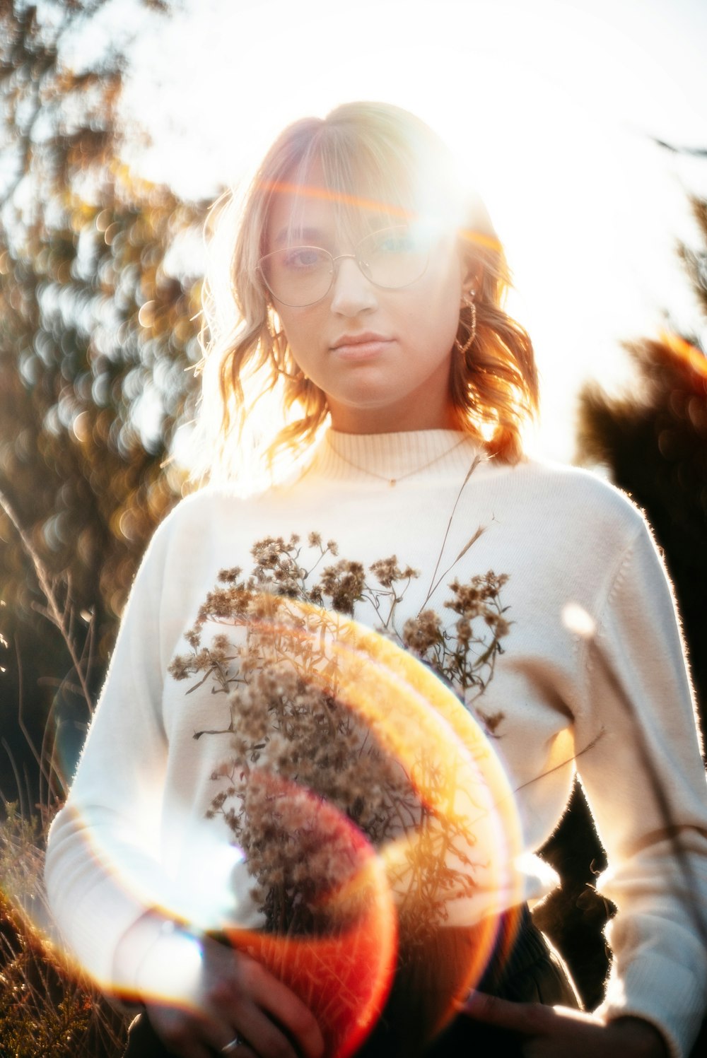 Mujer con camisa de manga larga floral blanca y marrón sosteniendo pastel blanco y marrón