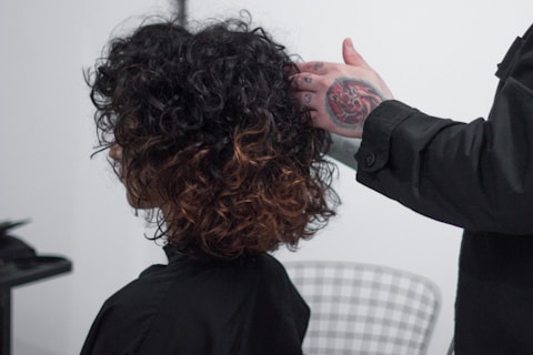 a woman getting her hair cut by a man