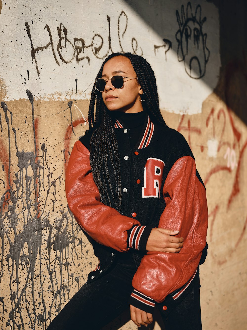 woman in black hijab and orange leather jacket leaning on wall