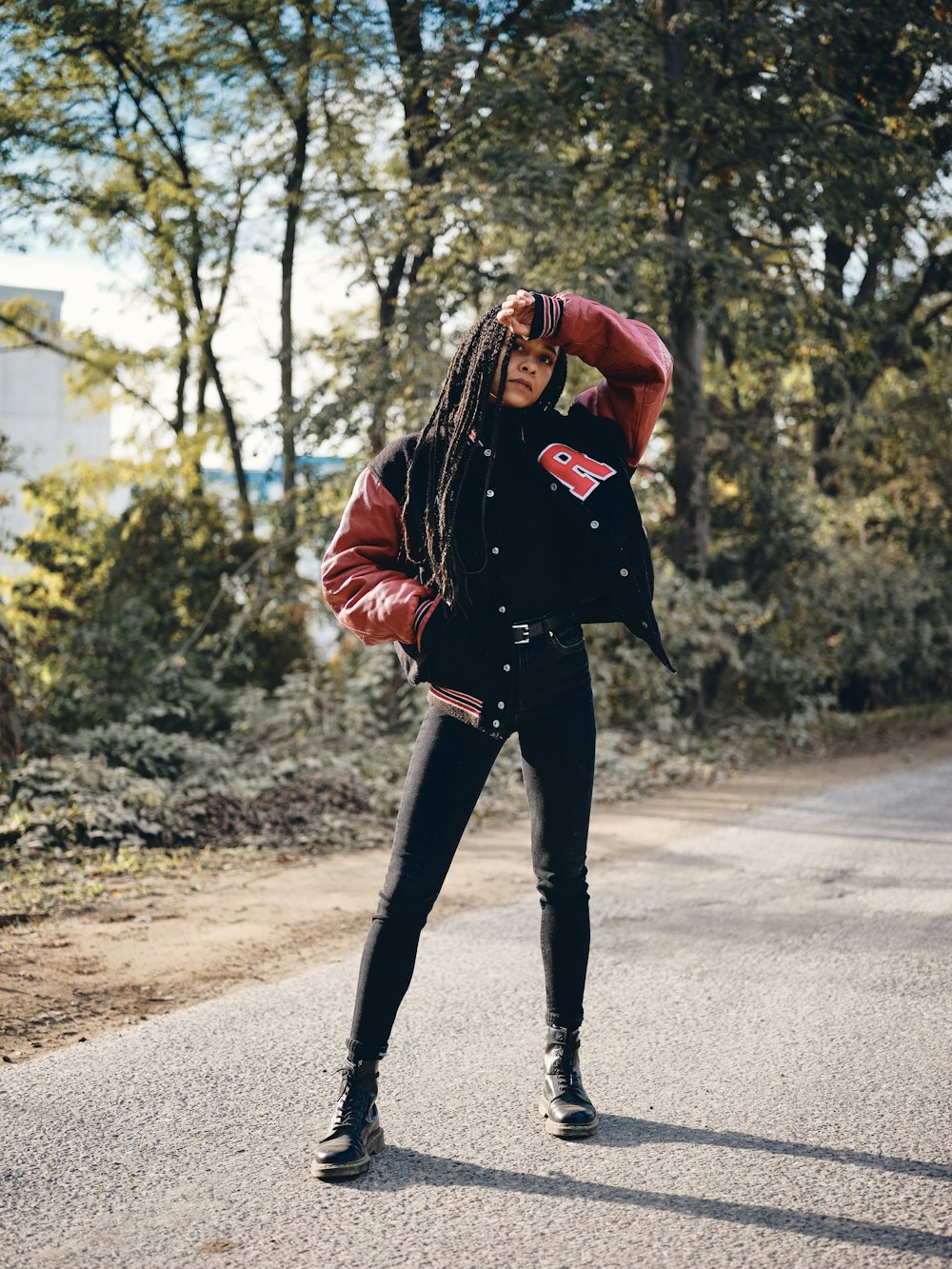 woman in black leather jacket and black pants standing on road during daytime