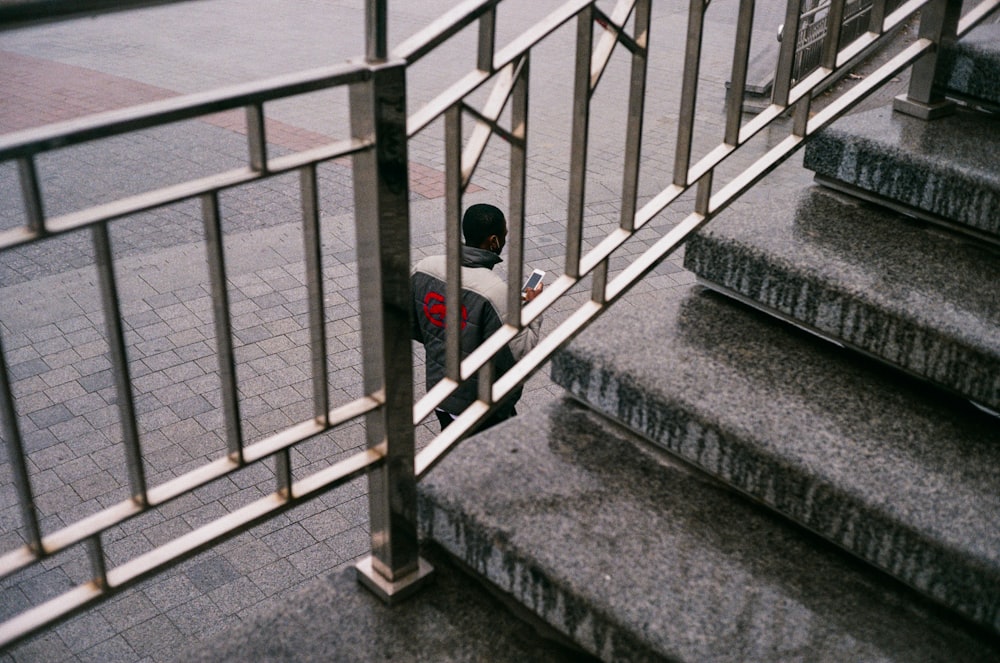 pessoa no capuz preto de pé na escada de concreto cinza
