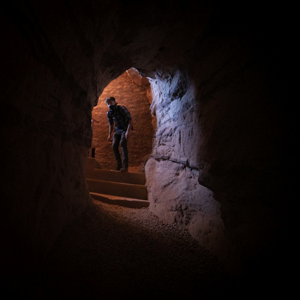 青いジャケットと黒いズボンを着た男が茶色のトンネルの中に立つ