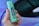 A hand is holding a green cylindrical container labeled 'HEMPACT CBD OIL 10%' with '1000mg Cannabidiol' written on it, against a blurred multicolored background.